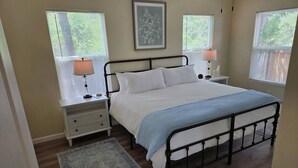 A bedroom with a bed, nightstands, lamps, a rug, and a framed picture on the wall.