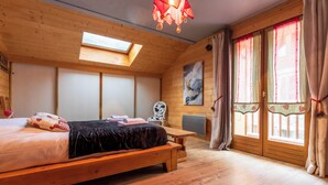 A cozy bedroom with a wooden bed, a skylight, a window with curtains, and a painting on the wall. - Chalet Laura, Ski & Authenticity (Les Belleville)