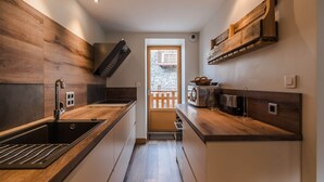 Eine moderne Küche mit Holzschränken, einer Edelstahlspüle und einem Einbauofen.