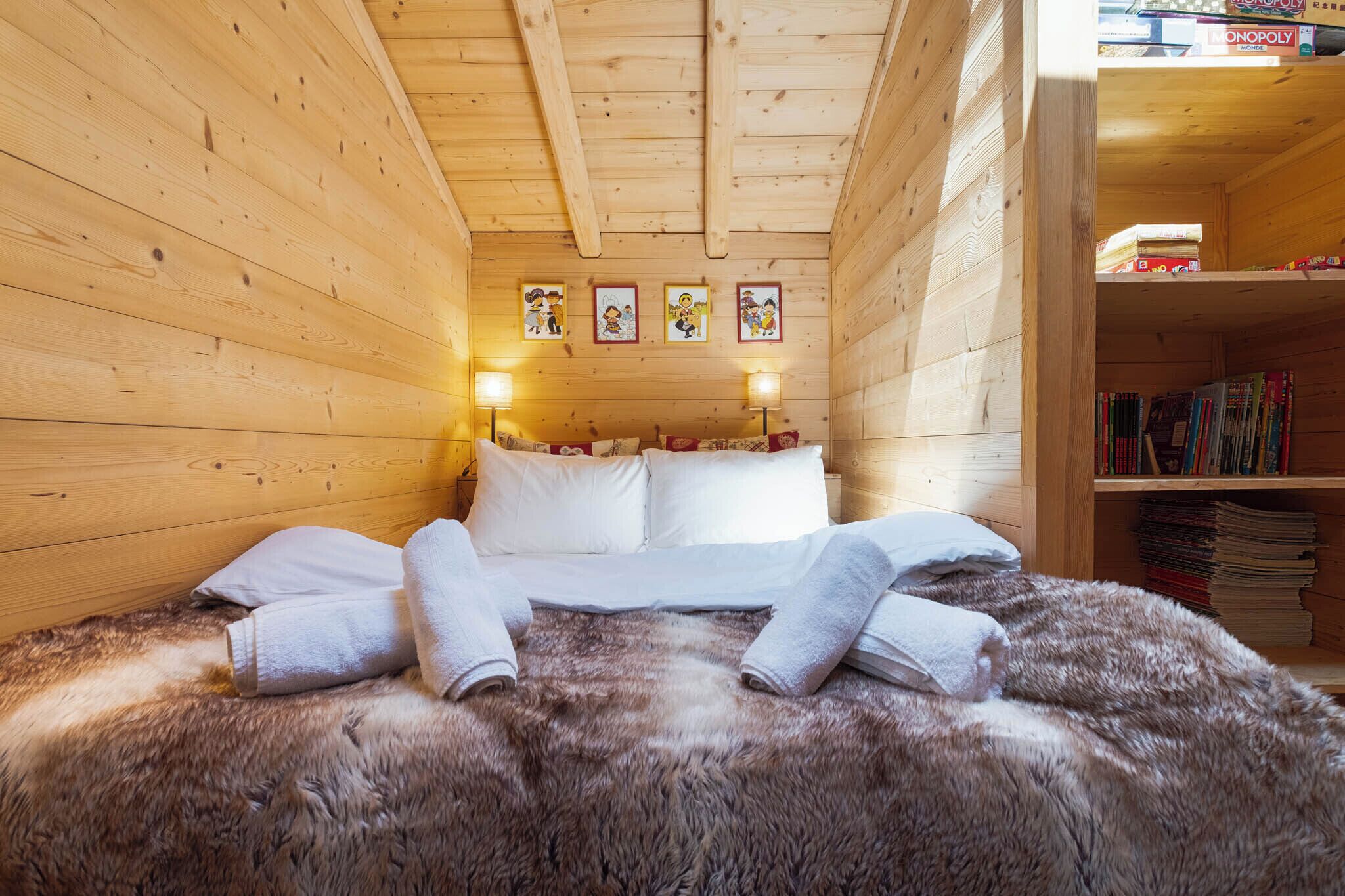 Acogedora habitación de cabaña de madera con cama, almohadas y una alfombra de piel.