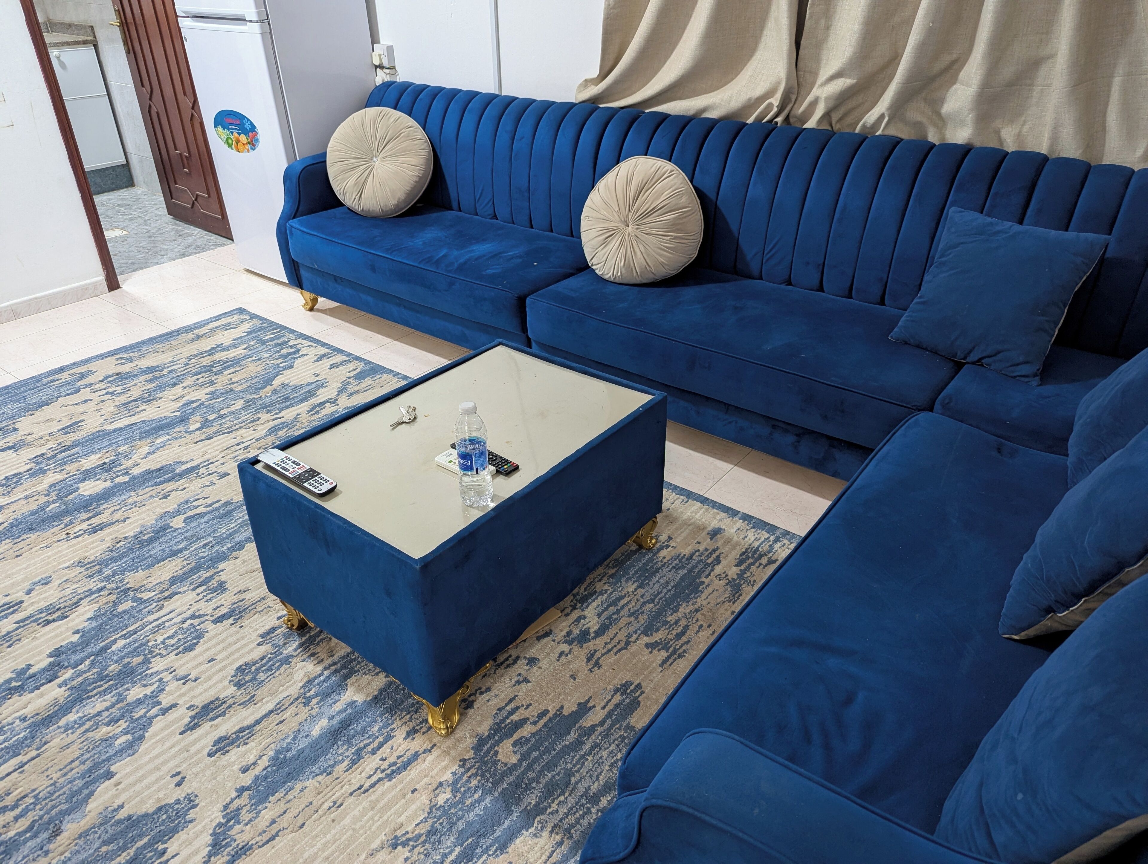 Ein modernes Wohnzimmer mit einem blauen Sofagarnitur, einem Couchtisch und einem gemusterten Teppich.