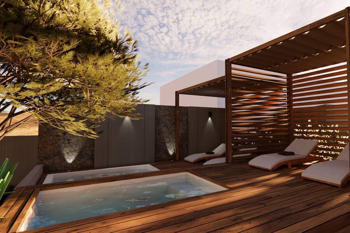 Une terrasse en bois dotée d’un jacuzzi et de chaises longues, entourée d’une pergola en bois et d’un mur en pierre.