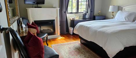 A hotel room with a fireplace, a bed, a TV, and a window with curtains.