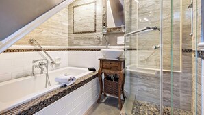 A modern bathroom with a freestanding bathtub, a glass-enclosed shower, and a vanity with a bowl sink. - The Ivy On Parker Guest House (Vancouver)