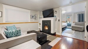 A living room with a fireplace, a television, and a sofa. - The Ivy On Parker Guest House (Vancouver)