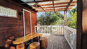 A wooden deck with a table and stools, a white railing, and a door. - Yingde Fenglin Moke Homestay (Yingde)