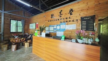 A reception desk with a wooden finish, a bulletin board with notices, and a menu board.