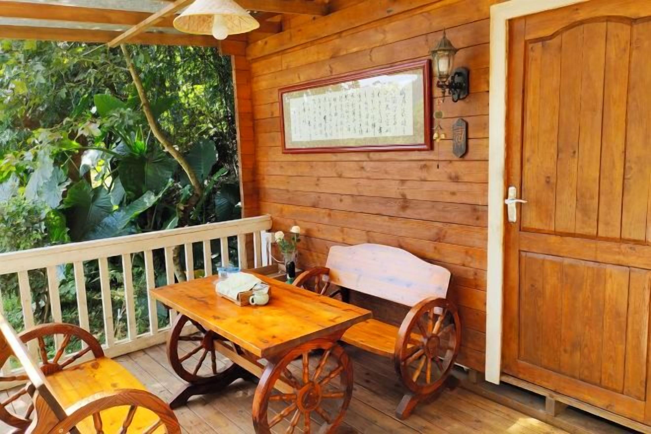 Une terrasse en bois avec une table et des chaises, un banc et une porte dotée d’un panneau en bois.