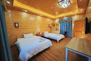 Two single beds with white linens, a table, and a TV are featured in this room.