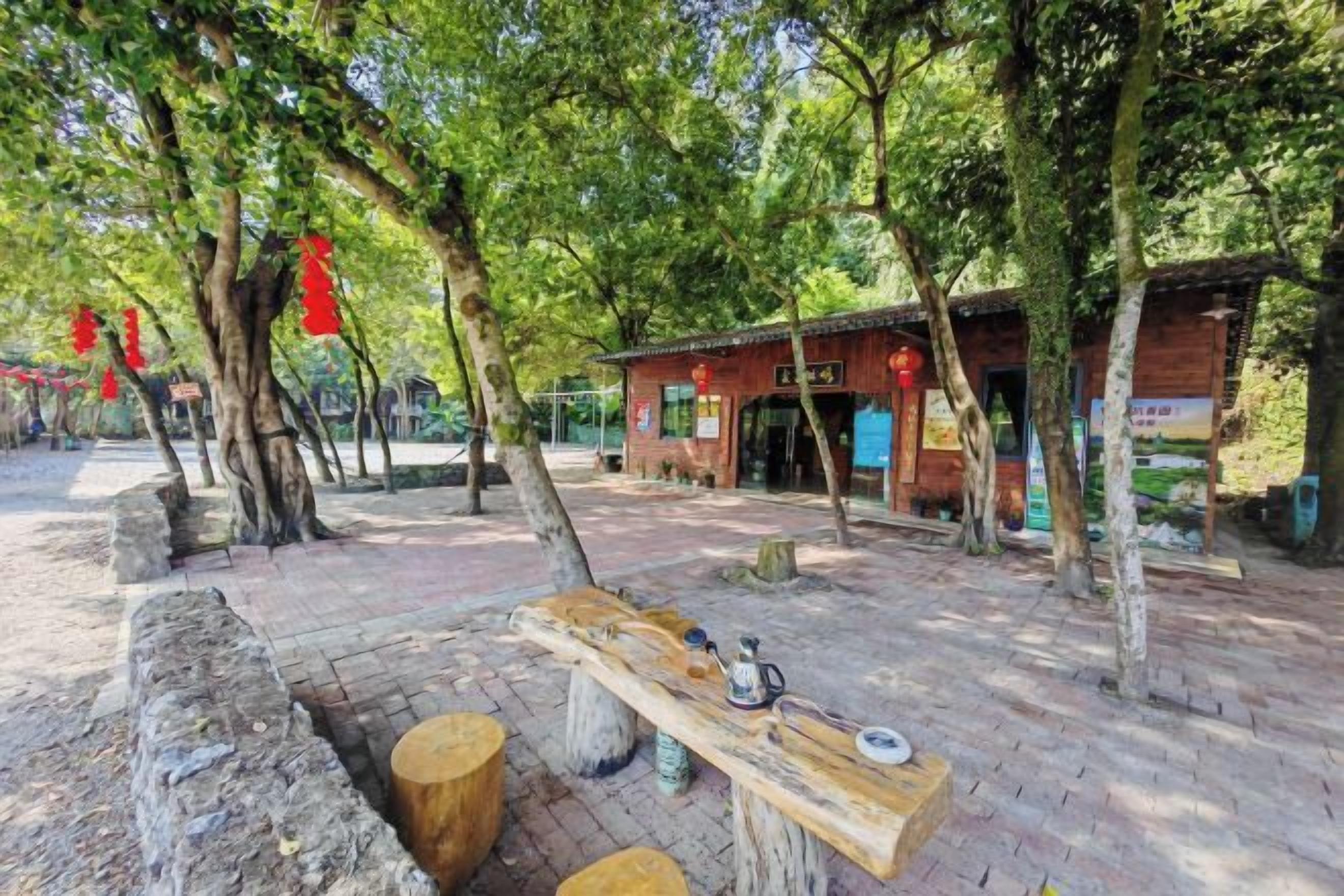 An outdoor seating area with a wooden bench, a table, and a trash bin.