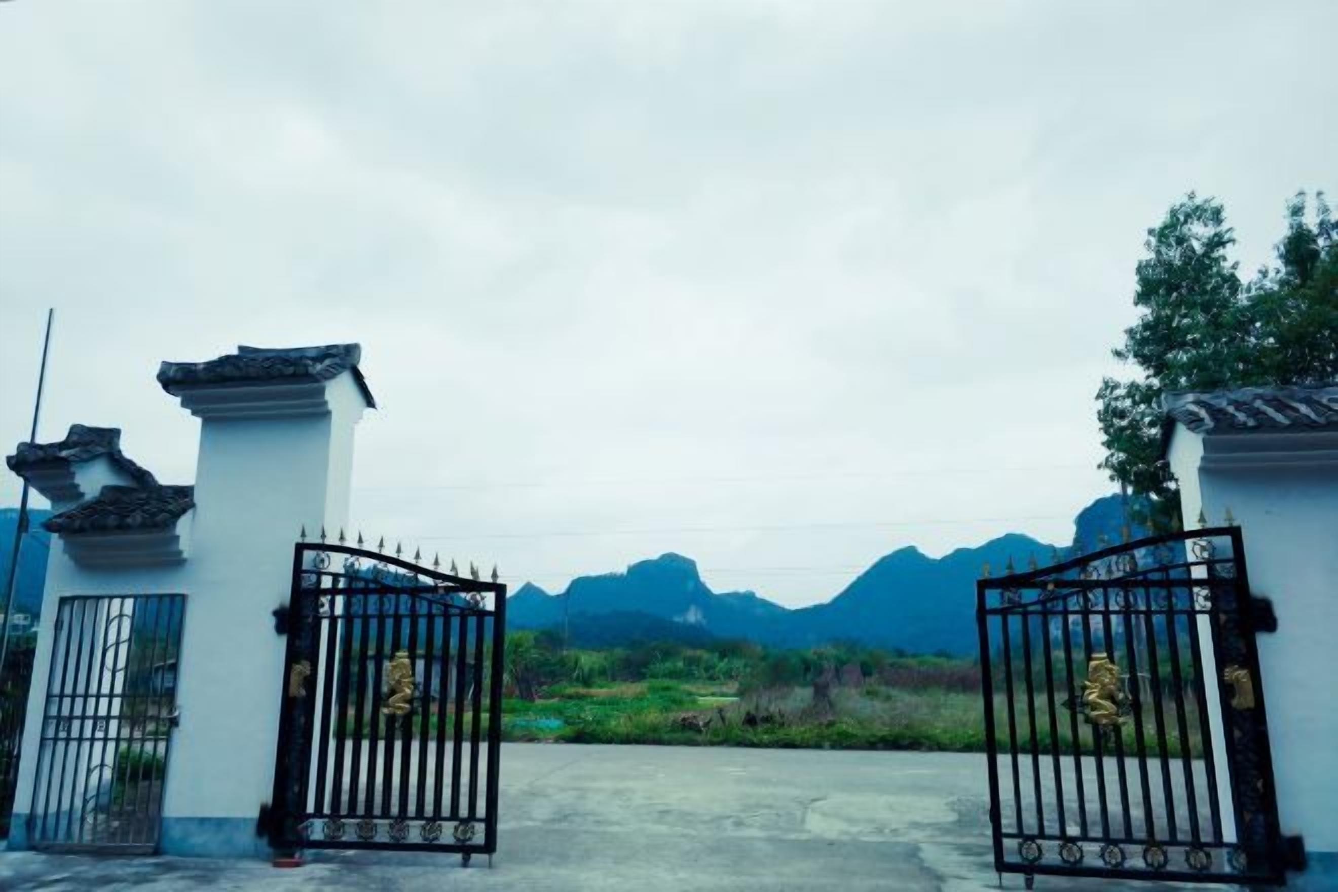 A gated entrance with traditional architectural elements and a mountainous backdrop.