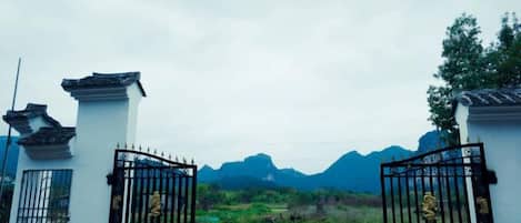 A gated entrance with traditional architectural elements and a mountainous backdrop.