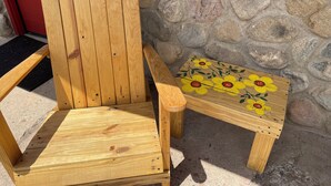 A wooden Adirondack chair with a backrest and armrests, positioned against a stone wall. - Historic Mora Inn and RV Park (Cleveland)