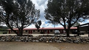 A motel with a red roof, stone walls, and a gravel driveway.