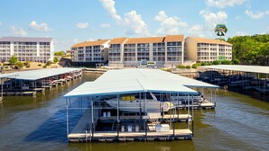 A marina with docked boats, a pool area, and a large building with multiple floors and balconies.