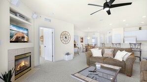 A spacious living room with a fireplace, a ceiling fan, and a television mounted on the wall.