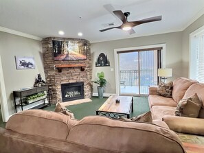 A living room with a fireplace, a ceiling fan, and a view through a sliding glass door.
