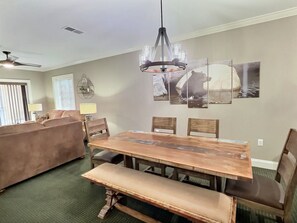 A dining area with a wooden table, benches, and a chandelier.