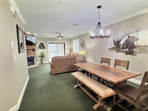 A dining area with a wooden table and benches, a ceiling fan, and a chandelier.