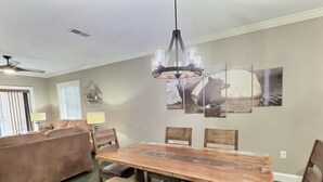 A dining area with a wooden table and benches, a ceiling fan, and wall-mounted artwork.
