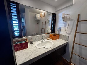Ein modernes Badezimmer mit einem großen Spiegel, einem Waschbecken und einer Holzkiste auf der Ablagefläche.