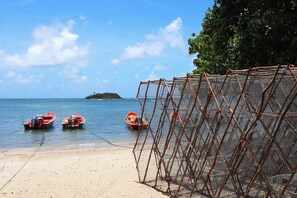 Ein Strand mit drei kleinen Booten, die an einer Netzkonstruktion festgemacht sind.