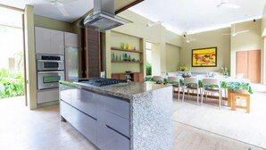 Una cocina moderna con una isla de granito, electrodomésticos integrados y un comedor con mesa y sillas.