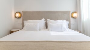 A neatly made bed with white linens and pillows, two bedside tables, and wall-mounted lighting fixtures. - Vacation Home 'Casa Ancla' with Sea View, Private Terrace and Air Conditioning (Unknown)