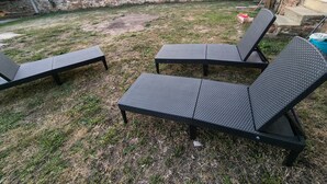 Un área de estar al aire libre con dos sillones y un muro de piedra al fondo.