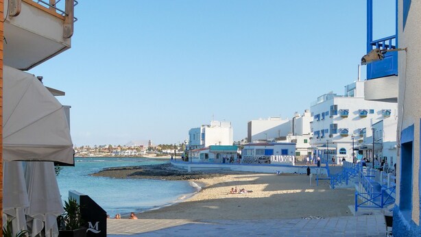 Un edificio costero con balcón que da a la playa.
