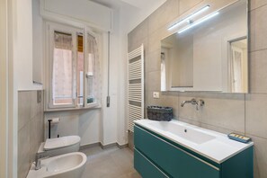 A bathroom with a white sink, a mirror, a towel rack, and a window with curtains.