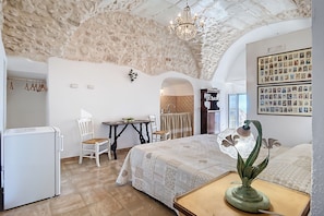 Une chambre à coucher comprenant un lit, un bureau, une chaise, un réfrigérateur et un lustre.