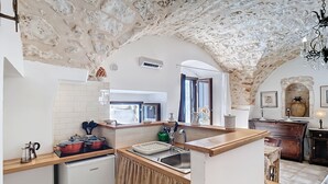Een keuken met een stenen plafond, een inbouwoven, een spoelbak en een houten aanrecht.