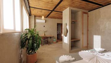 A room with a bed, a potted plant, a desk, and a hanging light fixture.