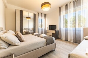 Una habitación de hotel moderna con una cama grande, un televisor, un escritorio y vistas al exterior.
