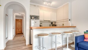 Uma cozinha moderna com armários brancos, bancada de madeira e quatro banquetas.
