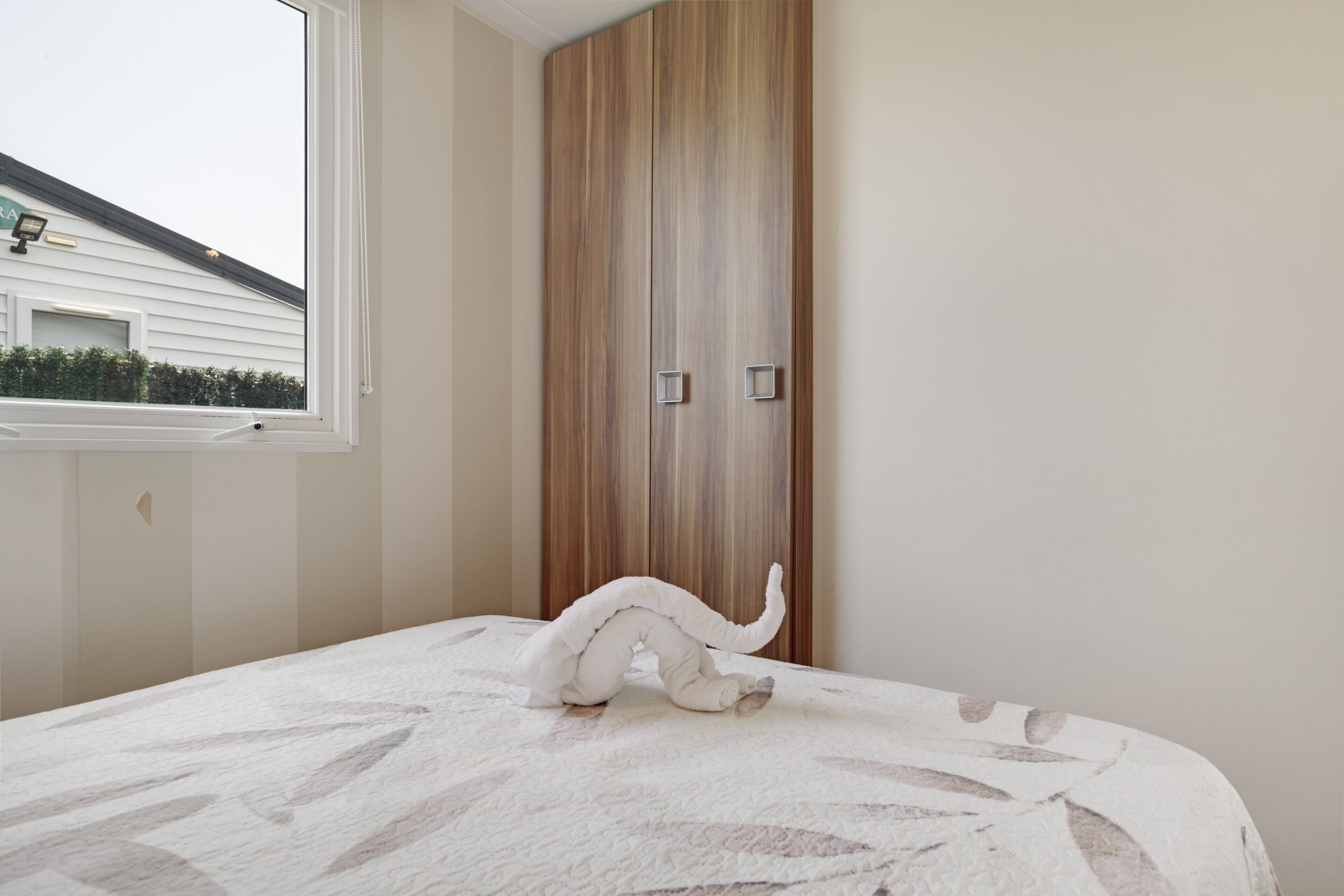 A bedroom with a bed, a window, and a wardrobe.