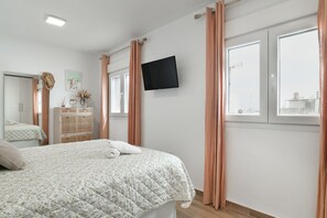A bedroom with a bed, a TV mounted on the wall, a dresser, and a window with curtains. - Apartment 'Boquerón' with Sea Views, Private Terrace and Wi-Fi (Conil de la Frontera)