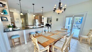 Una cocina amplia con una isla central, mesa de comedor de madera con sillas y una araña.