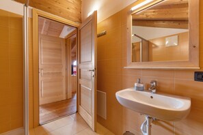 A bathroom with a wooden door, a sink, and a mirror.