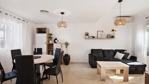 A modern living room with a dining area, black sofas, a coffee table, and pendant lights. - Holiday Home 'Estrella' with Mountain View, Wi-Fi and Air Conditioning (ayamonte)