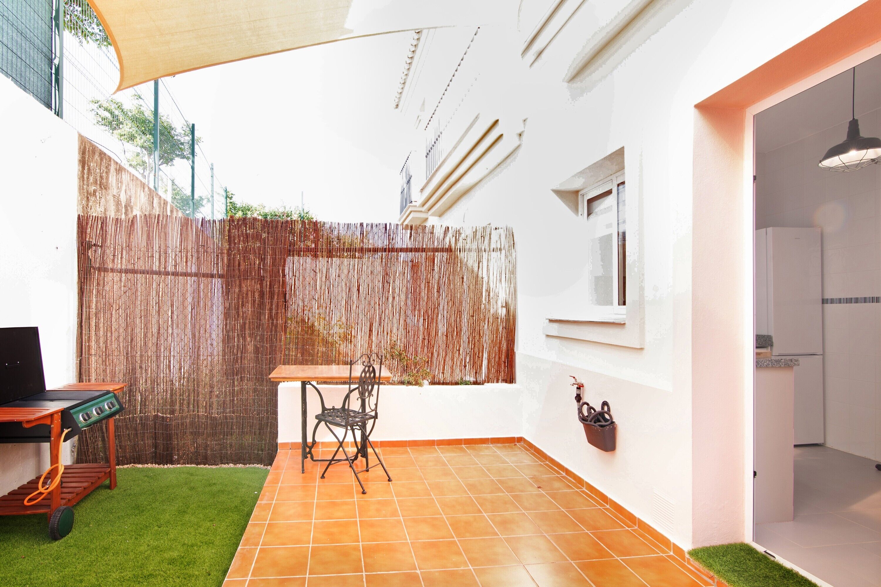 A patio with a table and chairs, a grill, and a wall-mounted basket.