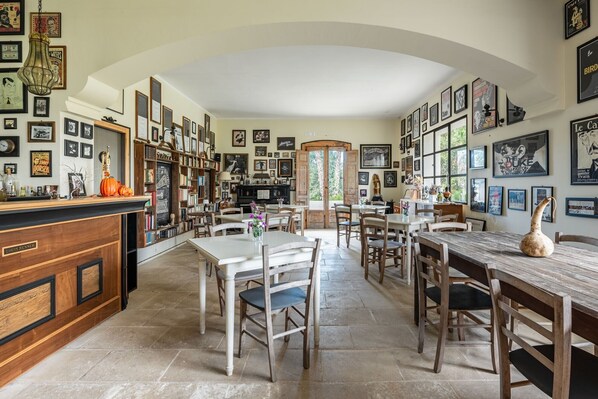 A spacious library with bookshelves, a fireplace, and a dining area with tables and chairs.