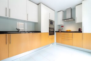 A modern kitchen with white and yellow cabinets, stainless steel appliances, and a black countertop. - Apartment 'Marina Formosa' with Shared Pool, Wi-Fi and Air Conditioning (Olhão)