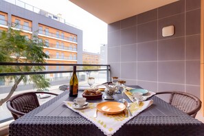 A balcony with a table set for breakfast, including bread, a bottle, and glasses. - Apartment 'Marina Formosa' with Shared Pool, Wi-Fi and Air Conditioning (Olhão)