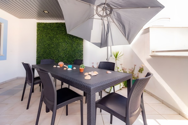 A dining area with a table, chairs, and an umbrella.