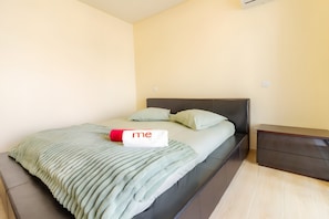 A neatly made bed with a blanket and pillows, a bedside table, and a nightstand.