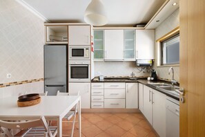 A compact kitchen with white cabinets, a microwave, oven, and a sink.