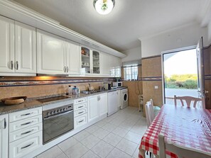 A kitchen with white cabinets, a built-in oven, a microwave, and a washing machine.