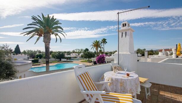A rooftop terrace with a pool, white chairs, a table with a glass, and a white tower structure. - Apartment 'Sail Golf Vilamoura' with Shared Pool, Wi-Fi and Air Conditioning (Quarteira)